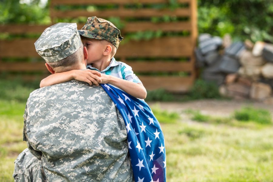 Boy hugs father in military uniform